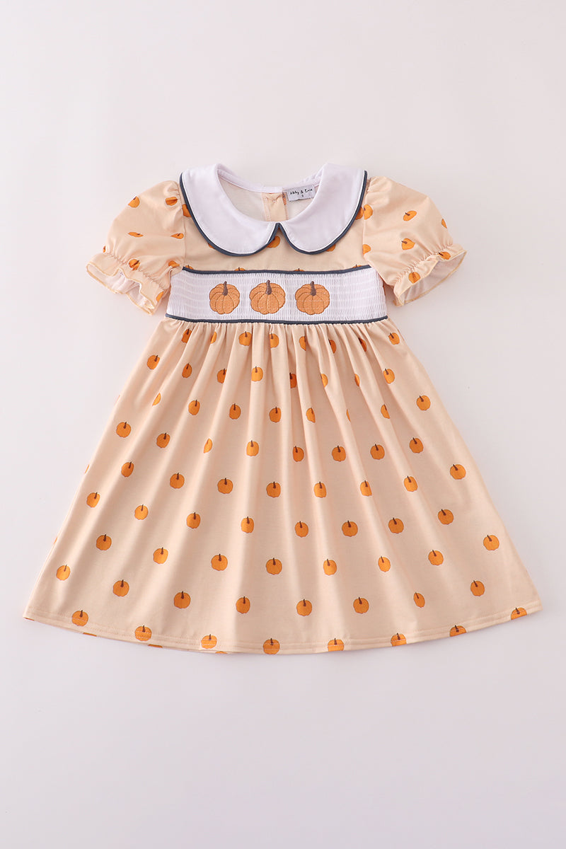 Beige dress with pumpkin pattern and white collar on a light gray background
