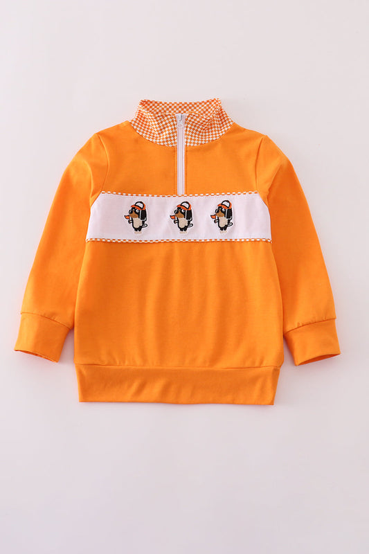 Orange sweatshirt with penguin design on a light gray background