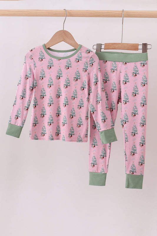Children's pajama set with tree pattern on pink fabric, hanging on a wooden rack.