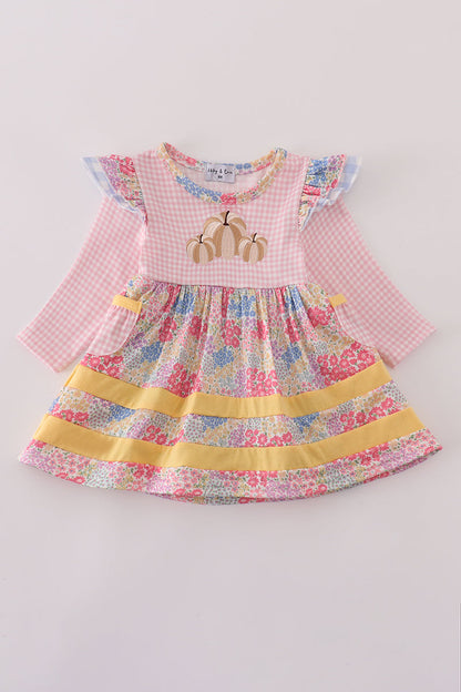 Children's dress with floral skirt and pink checkered top on a light gray background