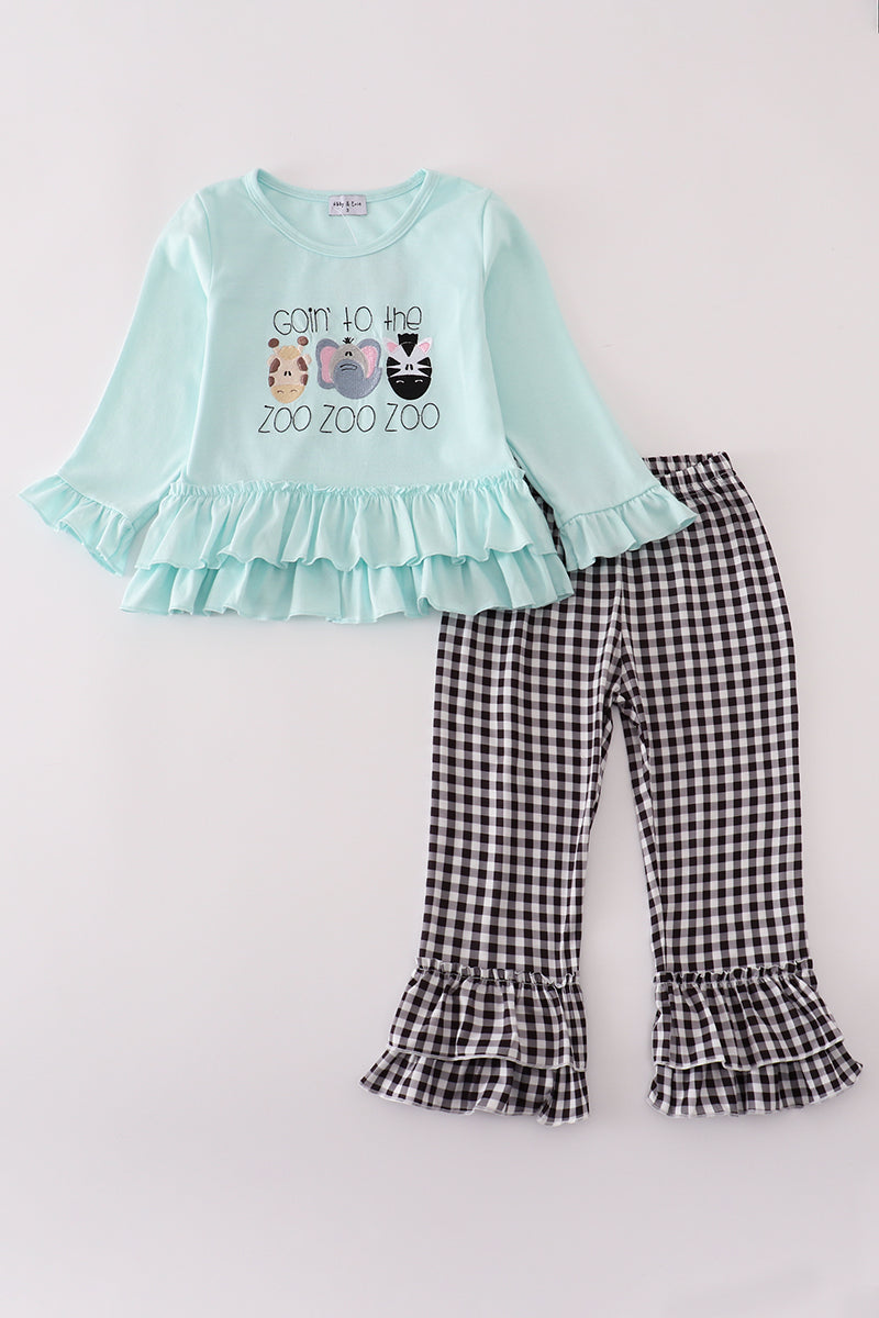 Children's outfit with light blue top and checkered pants on a white background