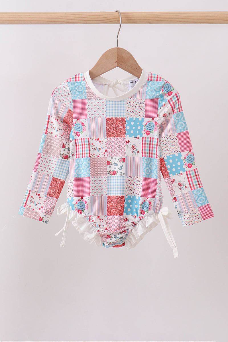 Children's boutique Pink Floral Patchwork Ruffle Rashguard. A playful mix of coordinating floral prints in a charming patchwork design, delicate ruffle detailing, and UPF 50+ sun protection make this rashguard the perfect combination of fashion and function for every water adventure.
