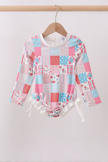Children's boutique Pink Floral Patchwork Ruffle Rashguard. A playful mix of coordinating floral prints in a charming patchwork design, delicate ruffle detailing, and UPF 50+ sun protection make this rashguard the perfect combination of fashion and function for every water adventure.