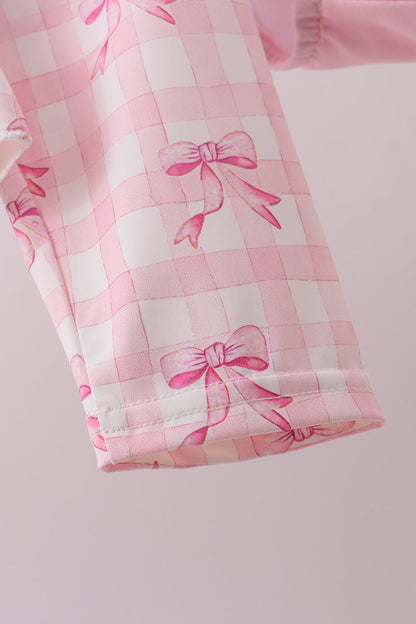 Pink checkered fabric with bow patterns on a light pink background