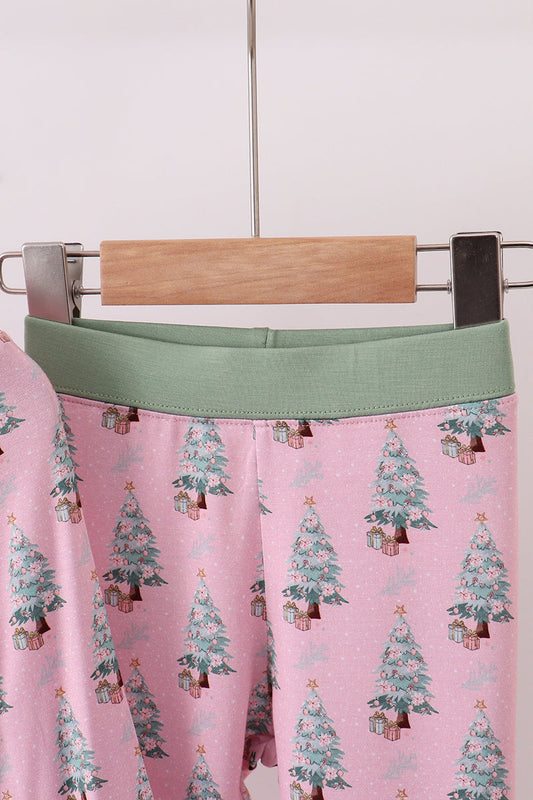 Pink pants with Christmas tree pattern on a hanger against a white background