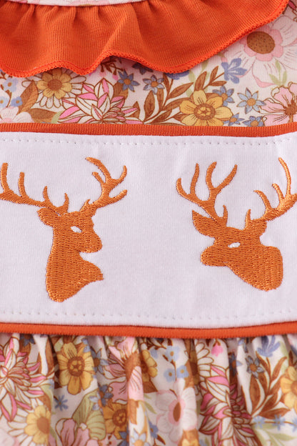 Close-up of a dress with floral pattern and deer embroidery on a white background