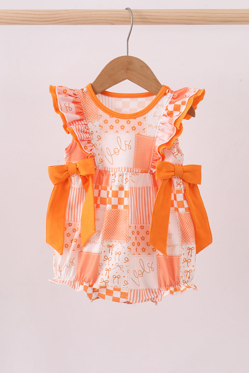 Orange and white checkered dress with ruffles on a wooden hanger against a white background