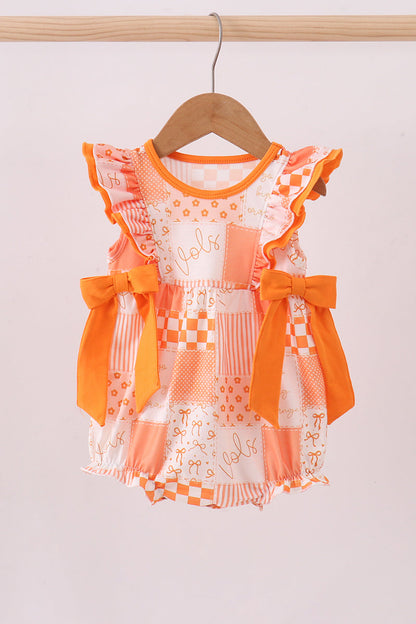 Orange and white checkered dress with ruffles on a wooden hanger against a white background